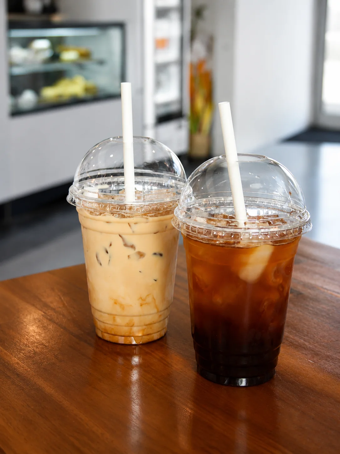 Two iced café drinks on a wooden table